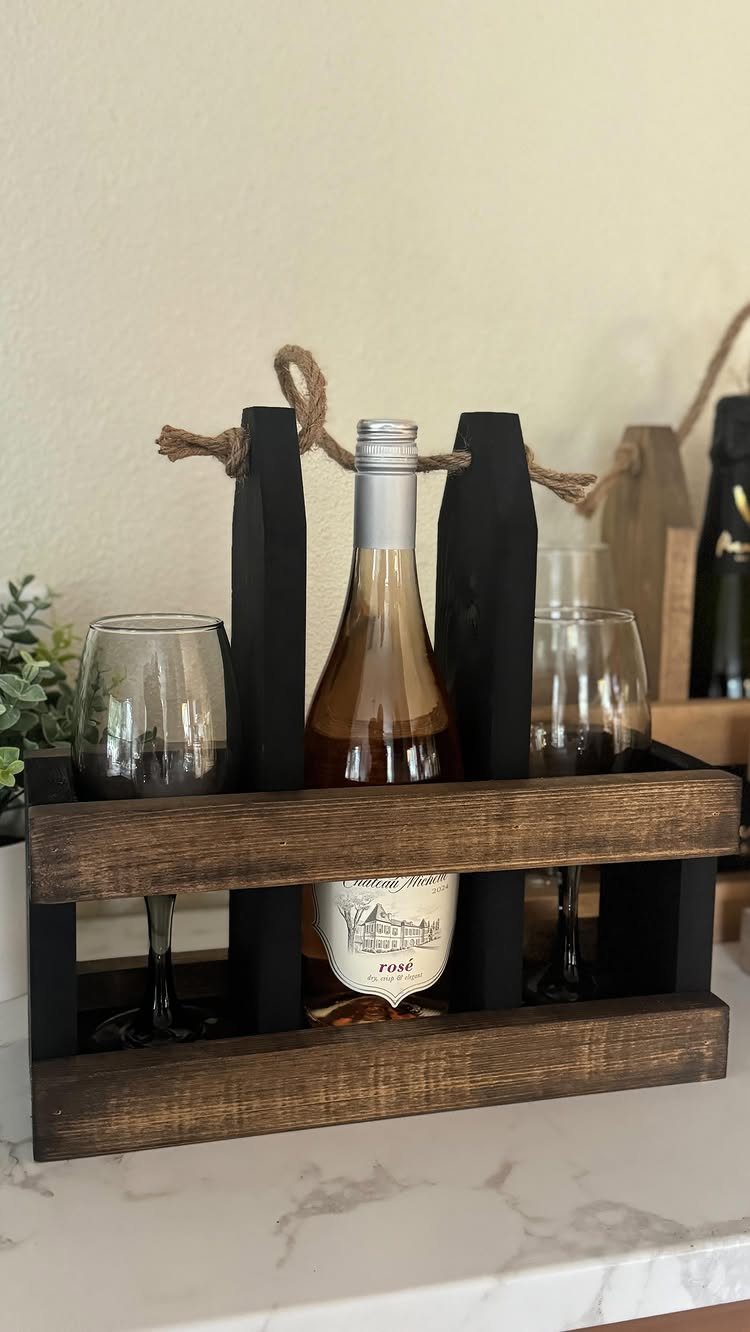Wooden wine carrier holding a bottle of rosé and two wine glasses.